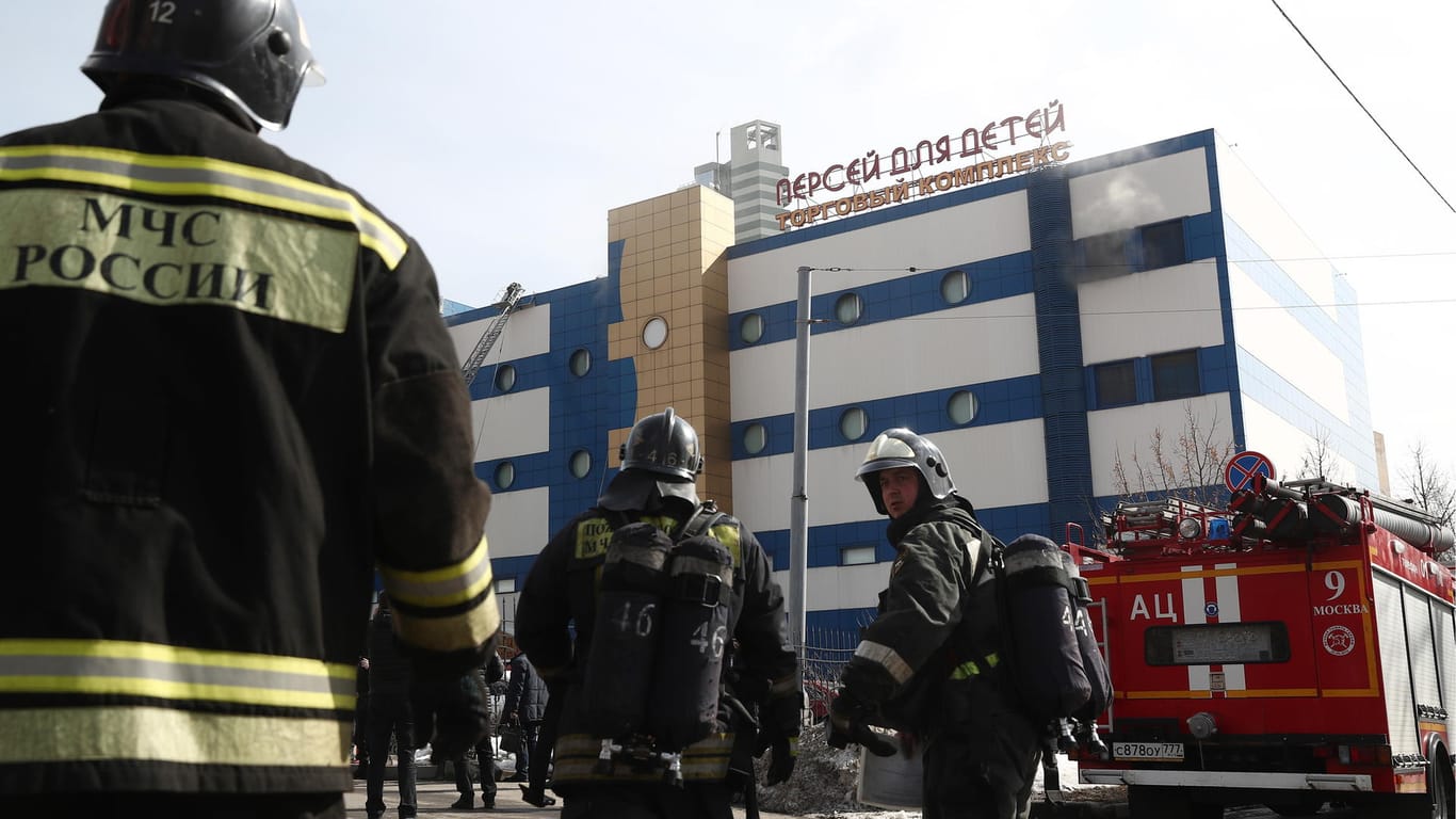 Feuerwehrleute stehen vor dem Einkaufszentrum "Persej dlja detej": 600 Menschen konnten aus dem brennenden Gebäude gerettet werden.