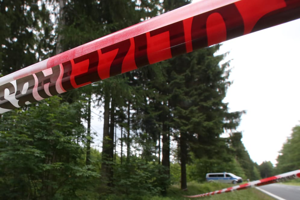 Ein Polizeiabsperrband durchtrennt ein Waldstück: Kinder haben beim Spielen in Barleben (Sachsen-Anhalt) ein menschliches Skelett gefunden. (Archivbild)