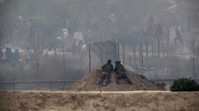 Israelische Soldaten beobachten bei Zusammenstößen zwischen palästinensischen Demonstranten und israelischen Soldaten im Gazastreifen die palästinensische Seite. Israelische Soldaten beobachten bei Zusammenstößen zwischen palästinensischen Demonstranten und israelischen Soldaten im Gazastreifen die palästinensische Seite.