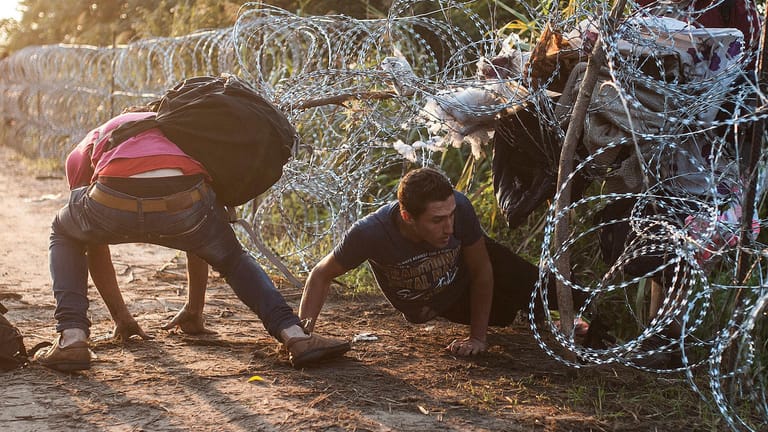 Flüchtlinge durchbrechen den Grenzzaun aus Stacheldraht zwischen Ungarn und Serbien: Kommt das neue Gesetz, könnte der Innenminister es Journalisten und NGOs verbieten, sich der Grenze zu nähern.