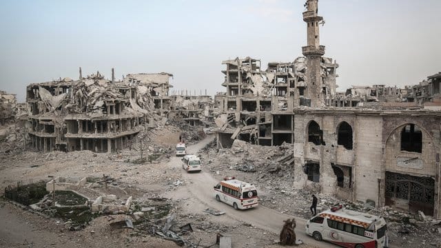 Fahrzeuge des Syrischen Roten Halbmonds fahren in Ost-Ghuta an völlig zerstörten Häusern vorbei. Fahrzeuge des Syrischen Roten Halbmonds fahren in Ost-Ghuta an völlig zerstörten Häusern vorbei.