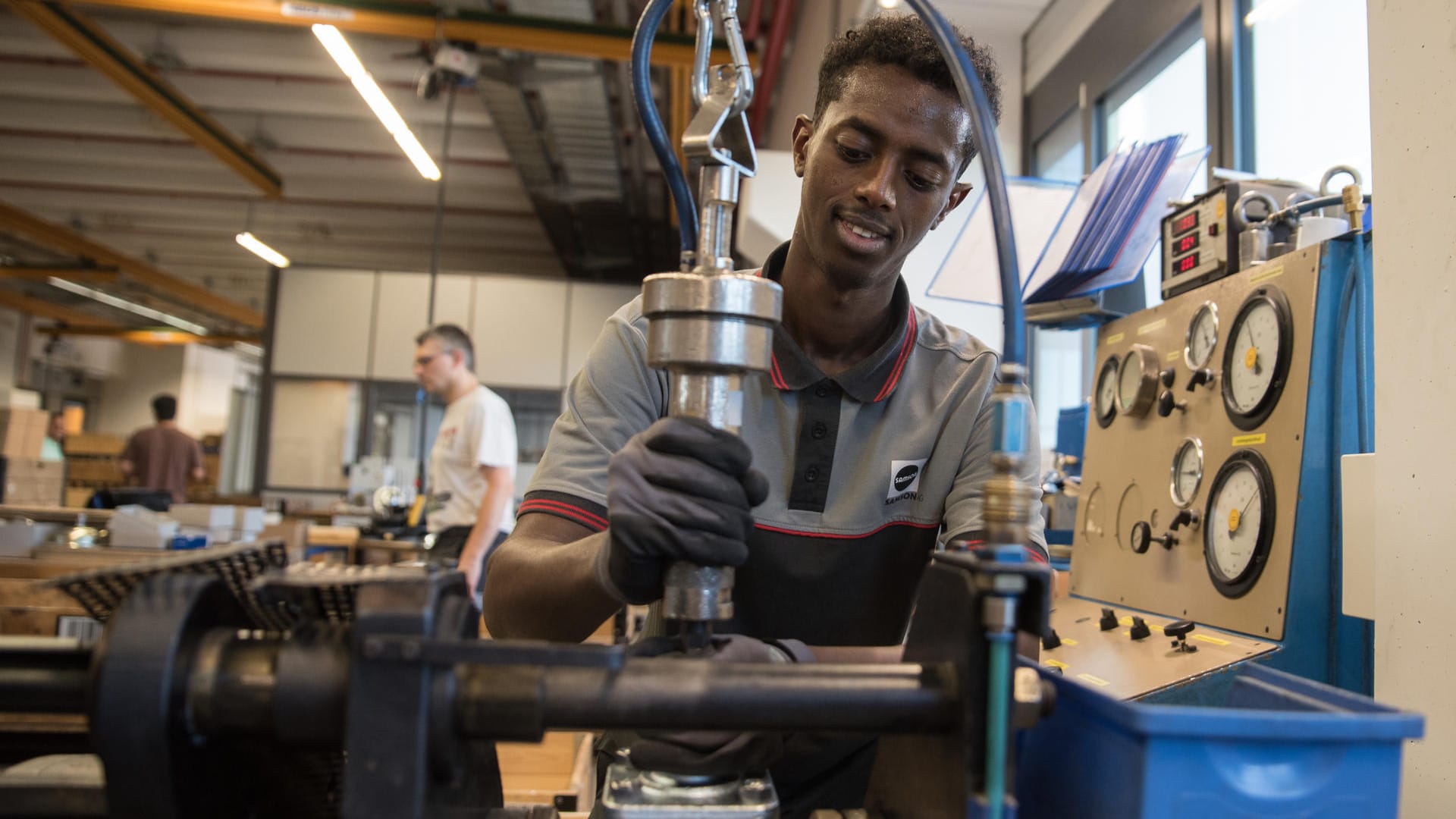 Abdisamed Abdullahi Mohamoud (19, aus Somalia) an einem Prüfstand für Regelventile: Industrie und handwerk fordern bessere Sprachbildung für Flüchtlinge in Deutschland.