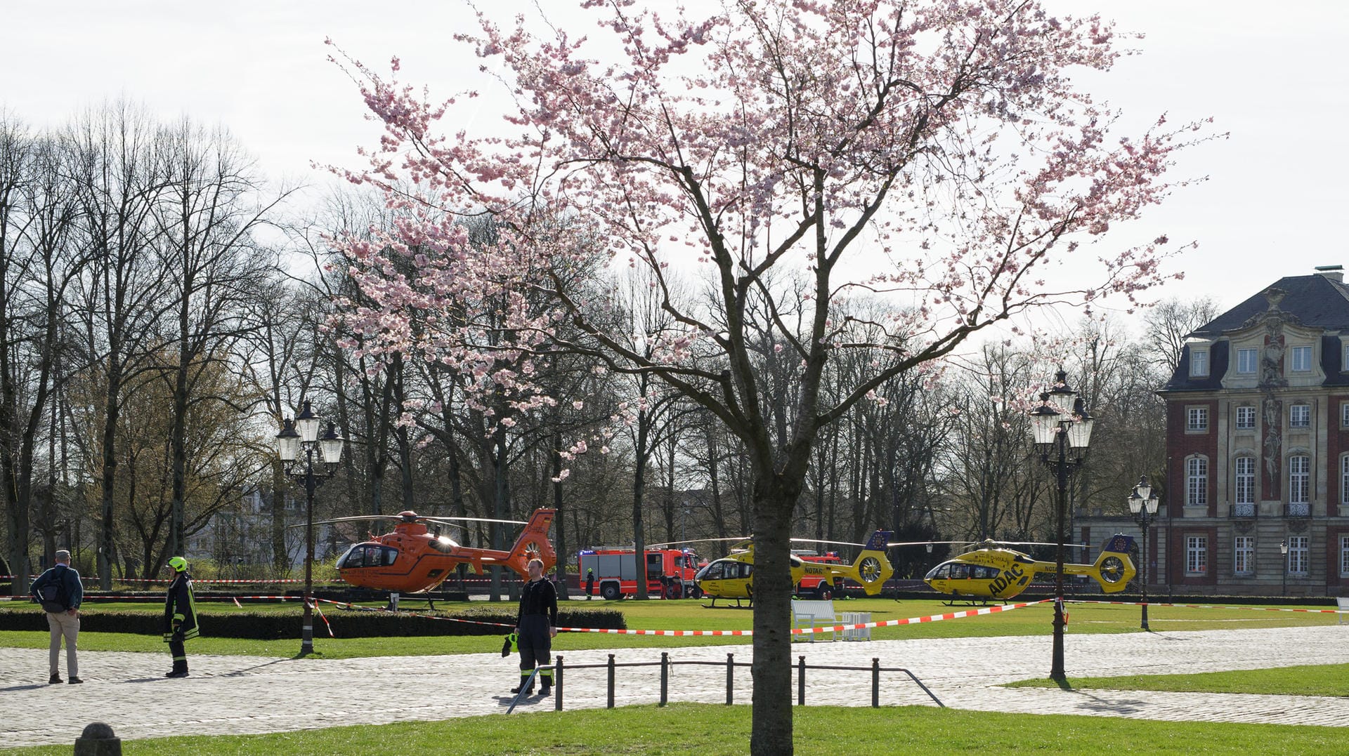 Rettungshubschrauber beim Botanischen Garten in Münster: Während Rettungskräfte die Verletzten des Attentats versorgen, genießen andere Menschen den beginnenden Frühling.