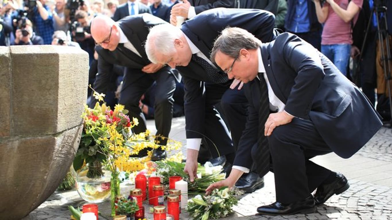 Münsters Oberbürgermeister Markus Lewe (CDU), Bundesinnenminister Horst Seehofer und der NRW-Ministerpräsident Armin Laschet legen vor dem Brunnen an der Gaststätte "Großer Kiepenkerl" in der Altstadt Blumen nieder.