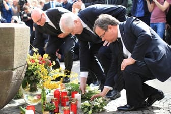 Münsters Oberbürgermeister Markus Lewe (CDU), Bundesinnenminister Horst Seehofer und der NRW-Ministerpräsident Armin Laschet legen vor dem Brunnen an der Gaststätte "Großer Kiepenkerl" in der Altstadt Blumen nieder.