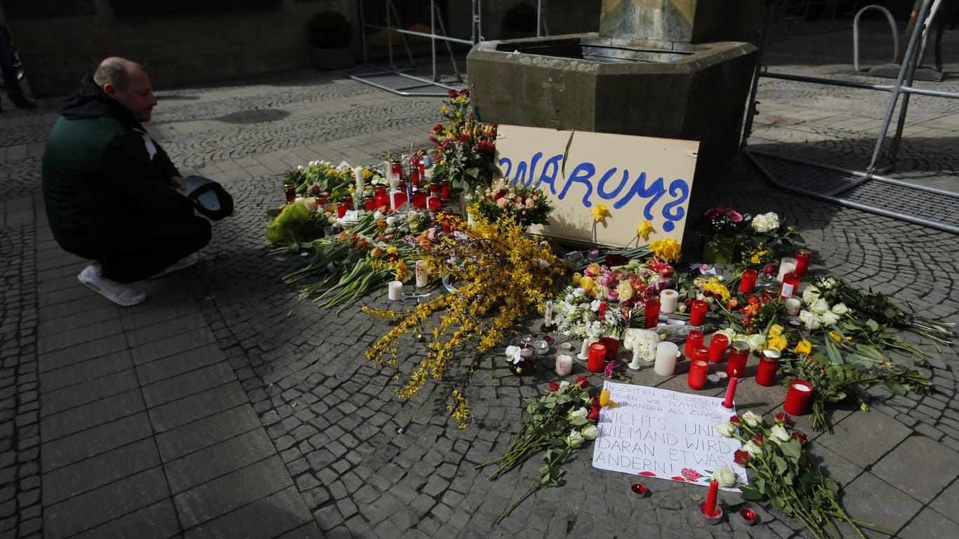 Trauer nach der Amokfahrt in Münster: Ein Mann hat am Tatort Blumen abgelegt, auf einem Schild steht schlicht "Warum?".