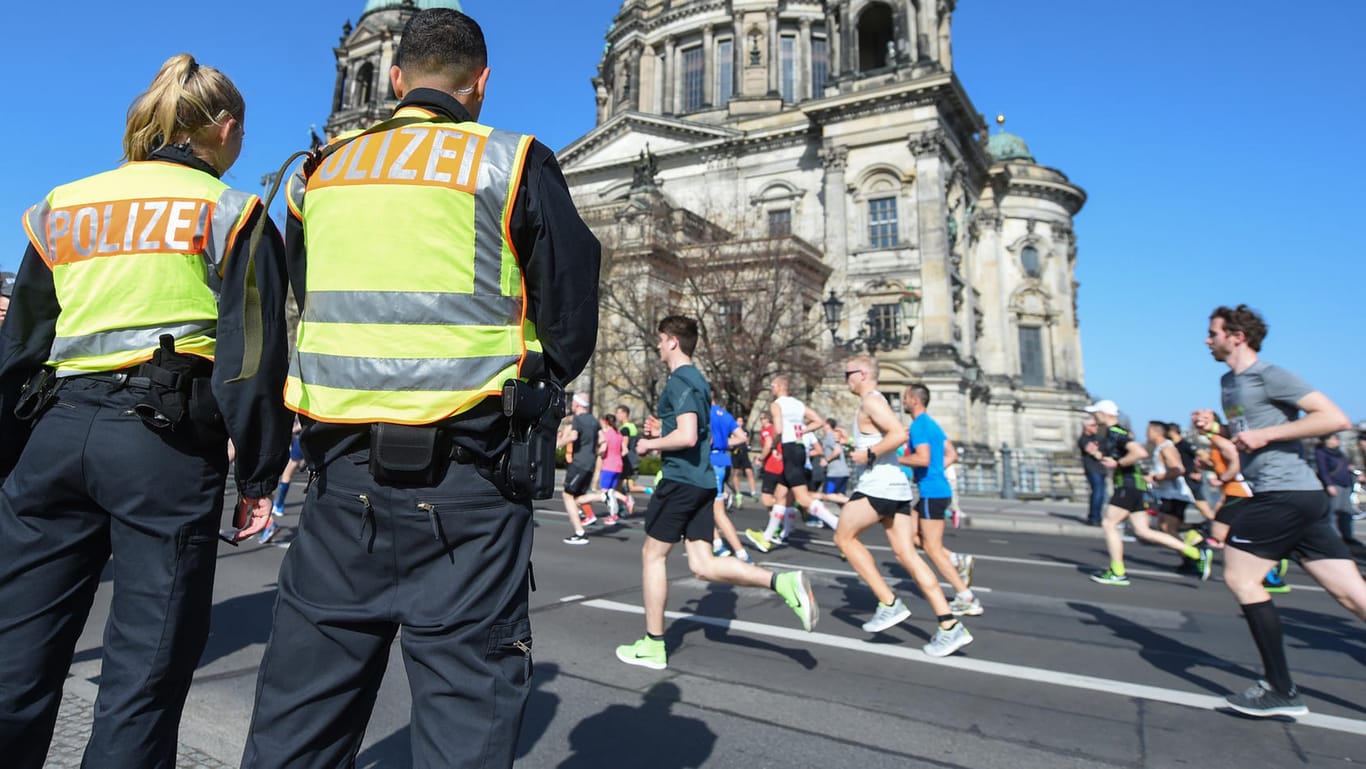 Zwei Polizisten stehen an der Halbmarathonstrecke in Berlin vor dem Dom: Der Terrorverdacht auf die Sportveranstaltung hat sich offenbar nicht erhärtet.