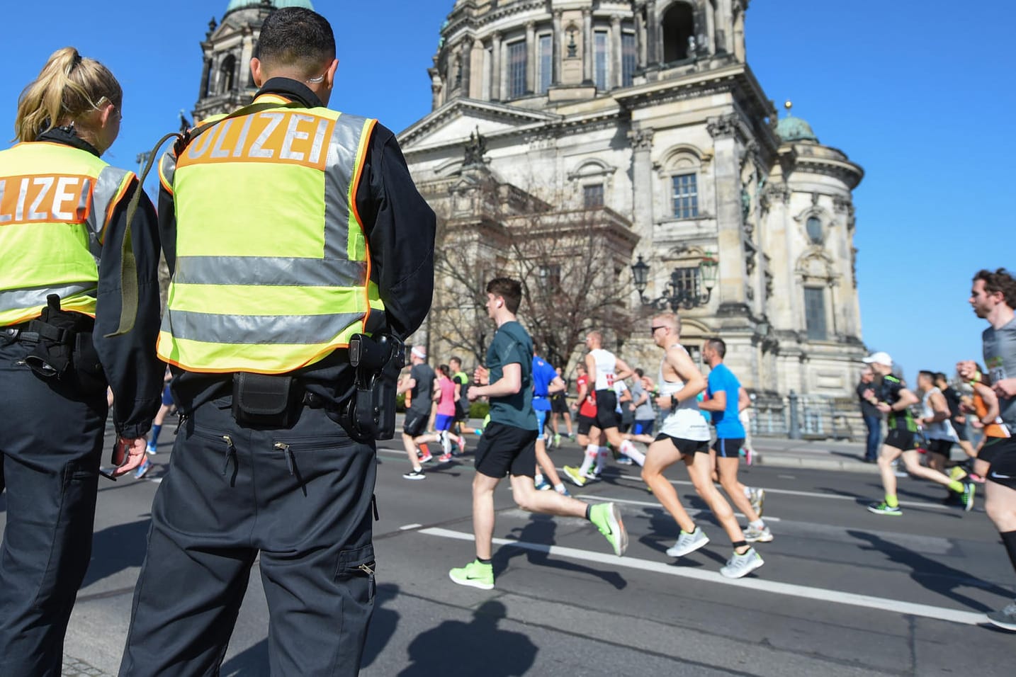 Zwei Polizisten stehen an der Halbmarathonstrecke in Berlin vor dem Dom: Der Terrorverdacht auf die Sportveranstaltung hat sich offenbar nicht erhärtet.
