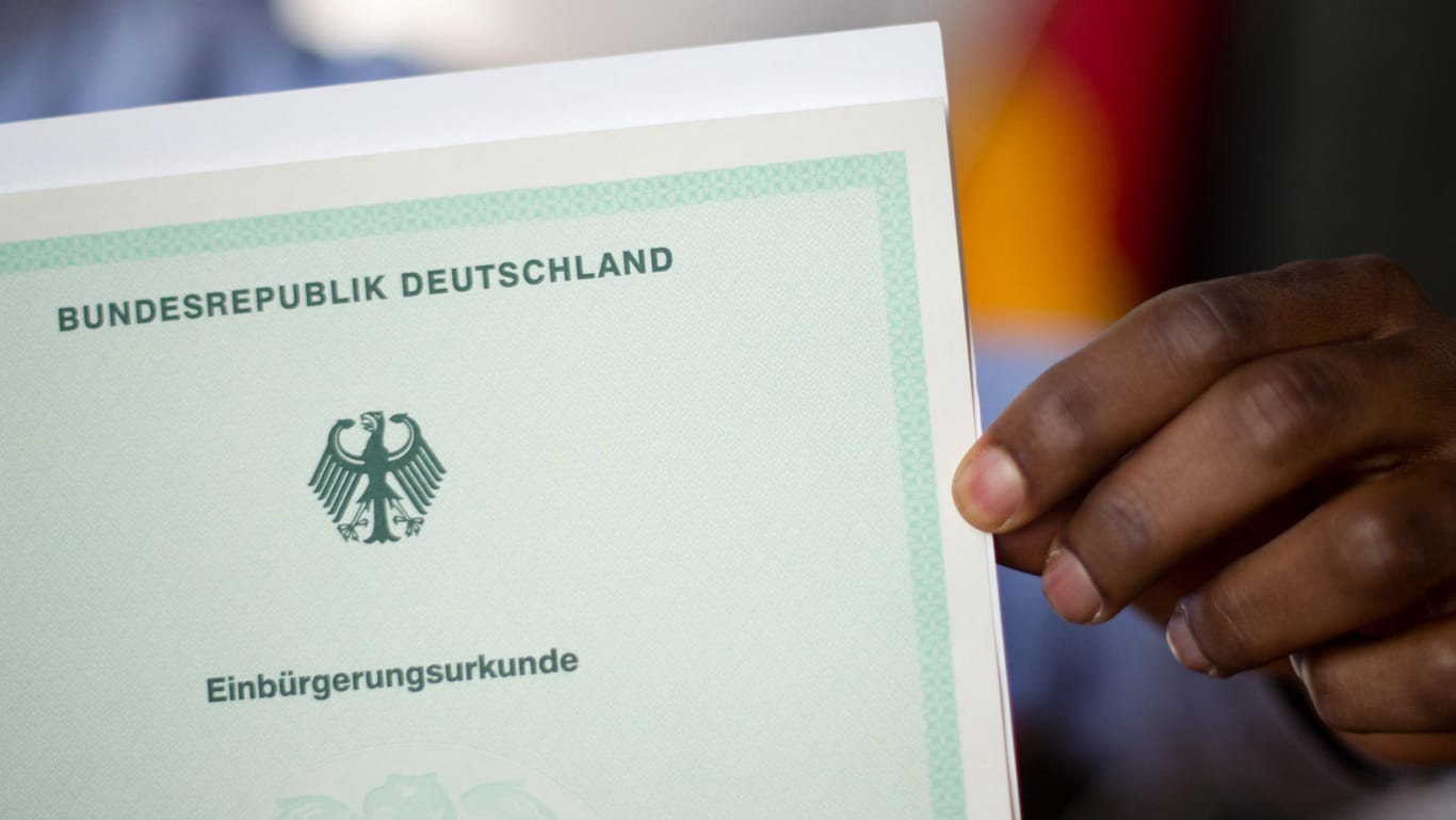 Ein Mann zeigt bei einer Einbürgerungszeremonie seine Einbürgerungsurkunde der Bundesrepublik Deutschland: Deutlich mehr Briten holen sich neue Staatsangehörigkeit in EU.