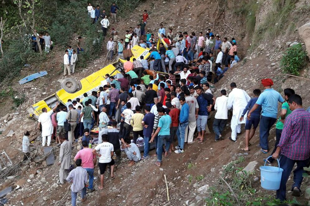 Ein mit Schulkindern besetzter Bus liegt am Hang in der Nähe einer Gebirgsstraße: Mindestens 23 Kinder im Alter von sechs bis elf Jahren seien bei dem Unfall im Bezirk Kangra im westlichen Teil des Himalaya ums Leben gekommen.