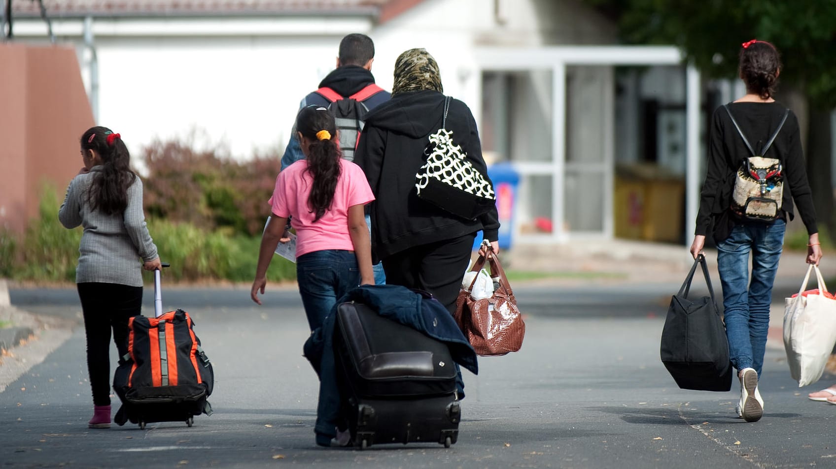 Flüchtlinge mit Koffern und Plastiktüten gehen an Unterkünften vorbei: Das Bundesverfassungsgericht wies eine Klage eines 13-jährigen Syrers zurück, der seine Mutter nach Deutschland holen wollte. Flüchtlinge mit Koffern und Plastiktüten gehen an Unterkünften vorbei: Das Bundesverfassungsgericht wies eine Klage eines 13-jährigen Syrers zurück, der seine Mutter nach Deutschland holen wollte.
