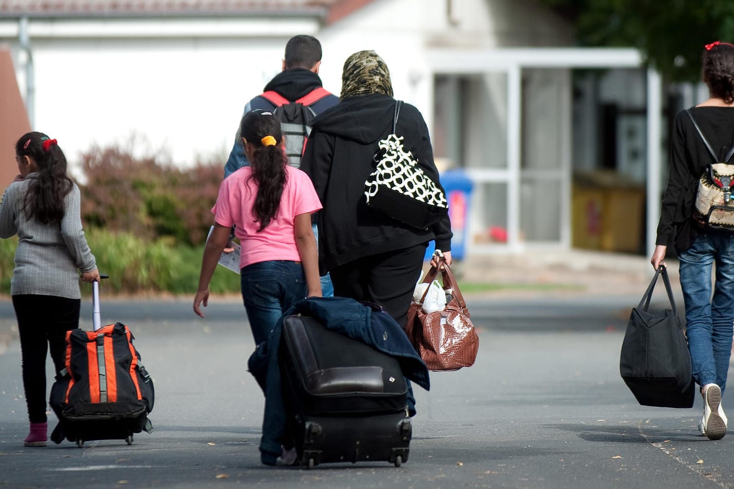 Flüchtlinge mit Koffern und Plastiktüten gehen an Unterkünften vorbei: Das Bundesverfassungsgericht wies eine Klage eines 13-jährigen Syrers zurück, der seine Mutter nach Deutschland holen wollte.