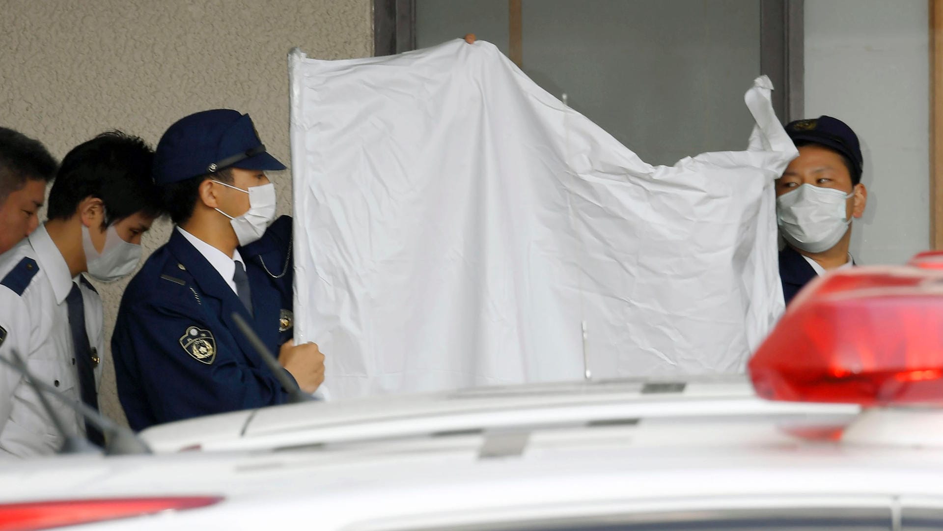 Polizisten verdecken das Gesicht des festgenommenen Japaners Yoshitane Yamasaki: Mann soll Sohn 20 Jahre lang in Käfig gehalten haben. Polizisten verdecken das Gesicht des festgenommenen Japaners Yoshitane Yamasaki: Mann soll Sohn 20 Jahre lang in Käfig gehalten haben.