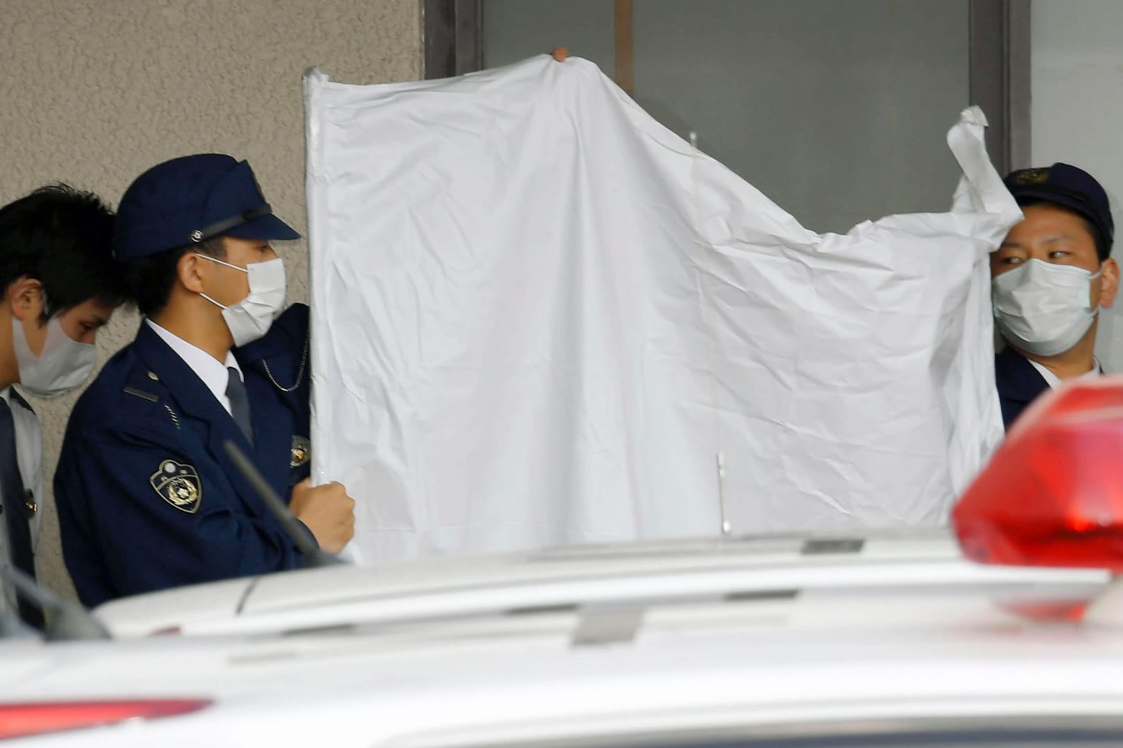 Polizisten verdecken das Gesicht des festgenommenen Japaners Yoshitane Yamasaki: Mann soll Sohn 20 Jahre lang in Käfig gehalten haben.