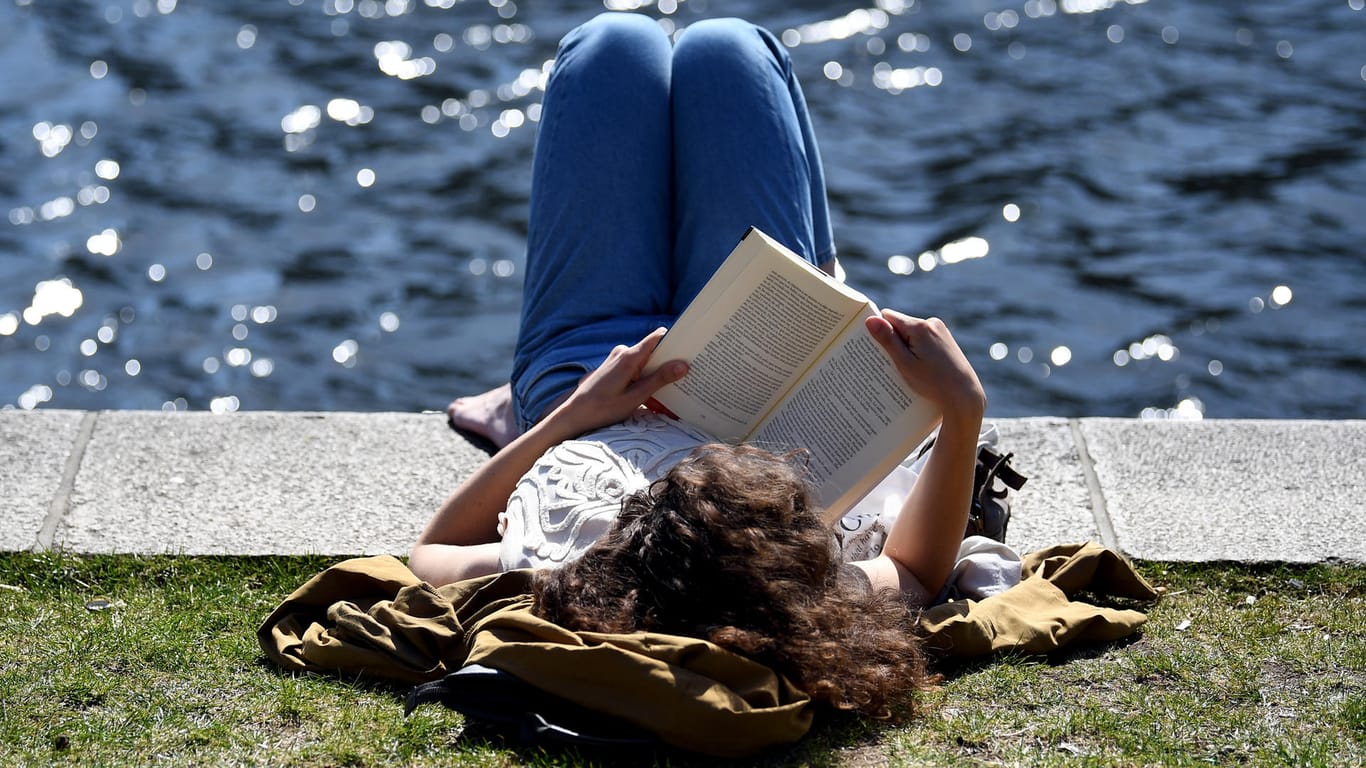 Eine Frau ließt ein Buch am Landwehrkanal: In vielen Teilen Deutschlands herrschen zurzeit sommerliche Temperaturen.