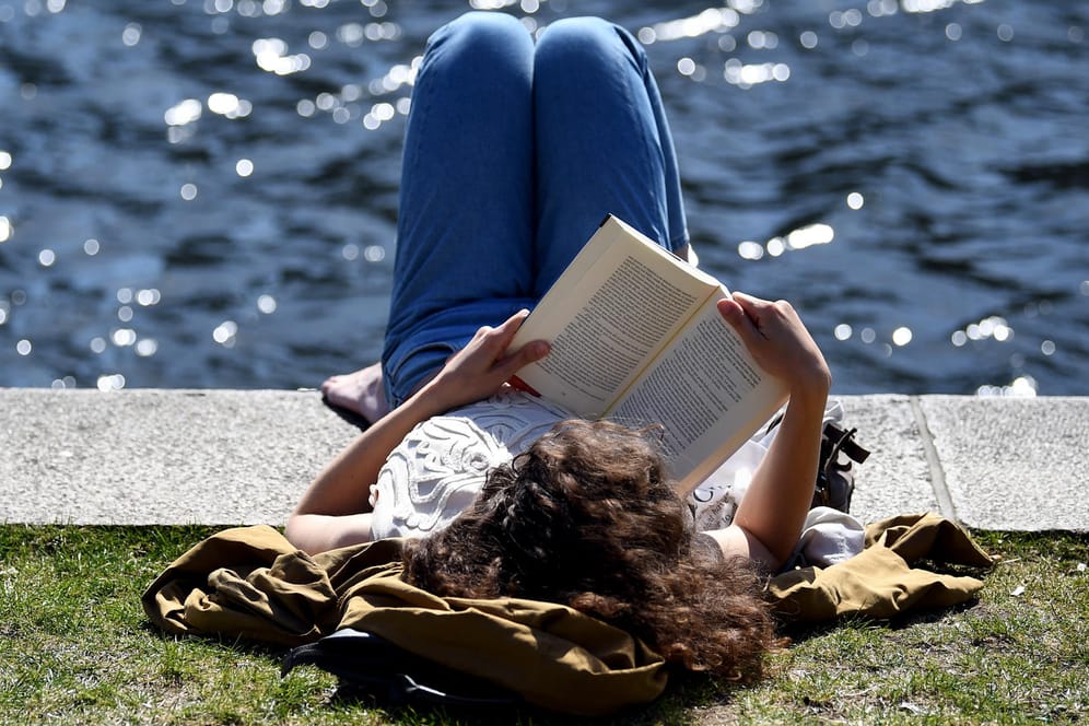 Eine Frau ließt ein Buch am Landwehrkanal: In vielen Teilen Deutschlands herrschen zurzeit sommerliche Temperaturen.