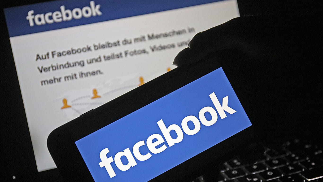 Ein Smartphone mit dem Logo von Facebook wird vor die Internetseite des sozialen Netzwerkes gehalten: Facebook startet Belohnungsprogramm für Datenmissbrauchs-Informanten.