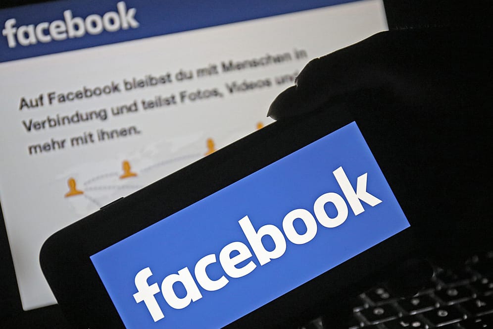 Ein Smartphone mit dem Logo von Facebook wird vor die Internetseite des sozialen Netzwerkes gehalten: Facebook startet Belohnungsprogramm für Datenmissbrauchs-Informanten.