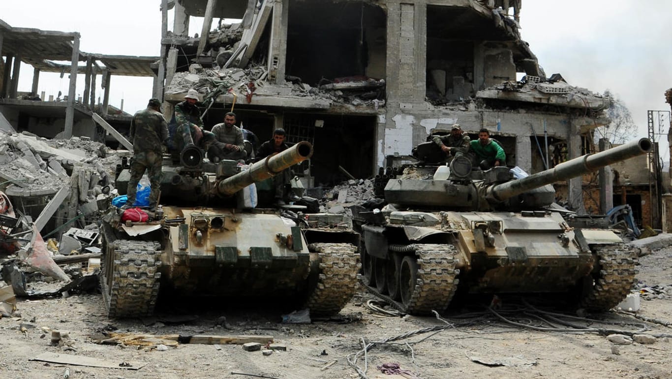 Panzer der syrischen Armee stehen vor einem zerstörten Gebäude in der umkämpften Region Ost-Ghuta: Die syrische Armee bereitet sich nach den Drohungen von Trump auf einen US-Angriff vor.