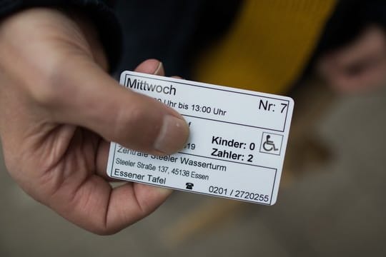 Ein Mann zeigt seine Berechtigungskarte vor dem Eingang zur Essener Tafel: Die Hilfsorganisation hatte seit dem 10.
