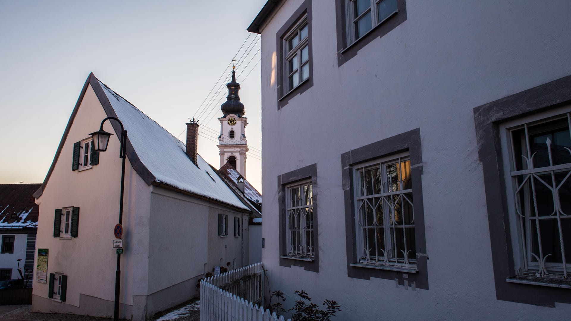 Vergitterte Fenster sind auf dem Gelände vom Kloster Altomünster an einem leerstehenden Klostergebäude vor dem Kirchturm der Kirche St. Alta zu sehen.