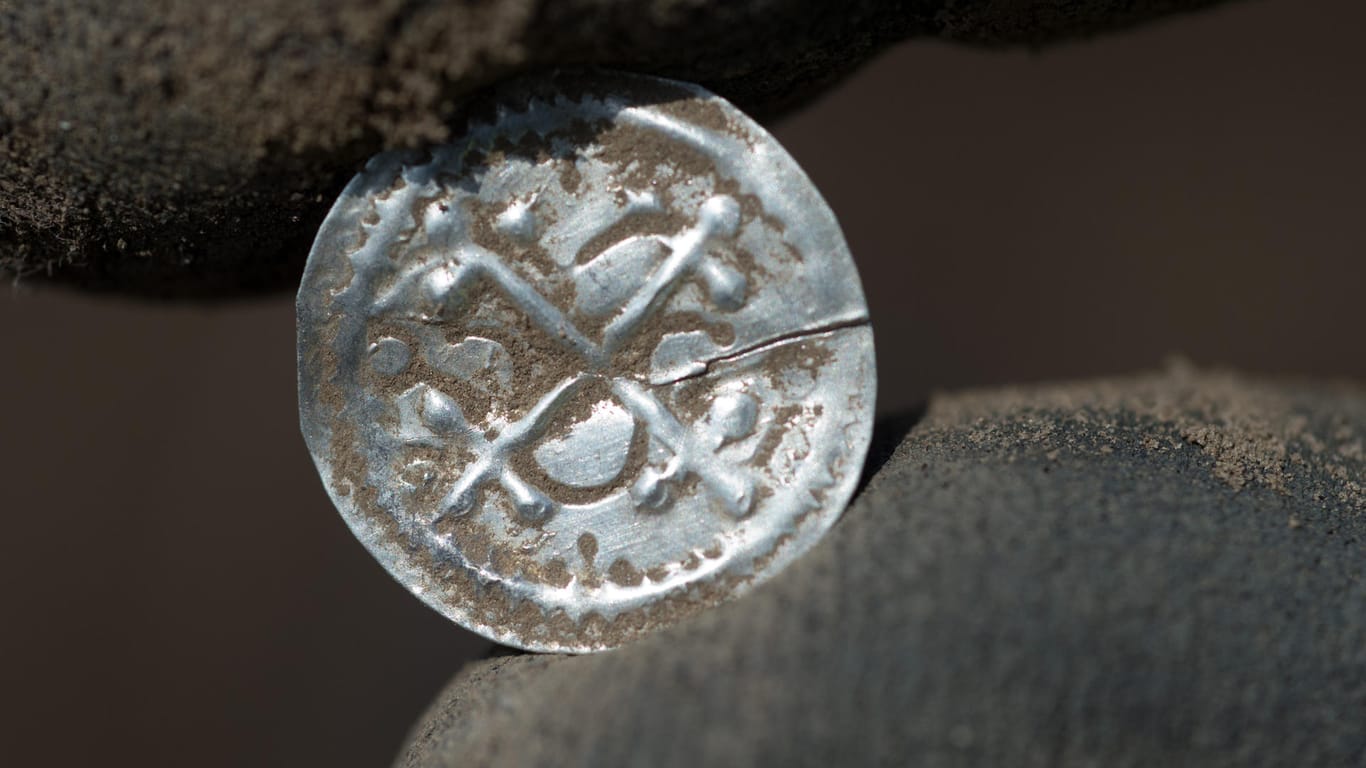 Ein Archäologe hält den ersten eigenständigen Münztyp Dänemarks (Kreuzbrakteate unter Harald Blauzahn) in der Hand: Ein 13-jähriger Schüler dachte zunächst, ein wertloses Stück Alu auf einem Acker gefunden zu haben.