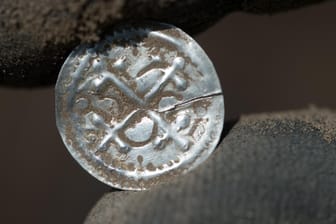 Ein Archäologe hält den ersten eigenständigen Münztyp Dänemarks (Kreuzbrakteate unter Harald Blauzahn) in der Hand: Ein 13-jähriger Schüler dachte zunächst, ein wertloses Stück Alu auf einem Acker gefunden zu haben.