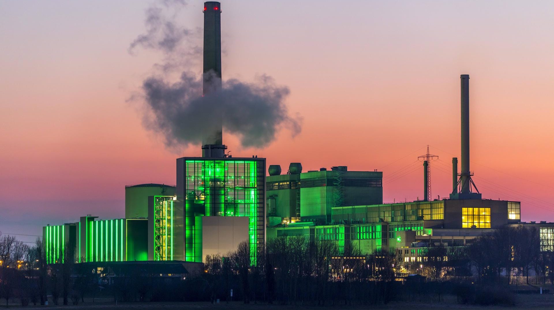 Das Heizkraftwerk Lausward in Düsseldorf, Gas- und Dampfturbinenkraftwerk, betrieben von den Stadtwerken Düsseldorf und EnBW, im Hafen von Düsseldorf am Rhein, grün beleuchtetes Stadtfenster, der Kamin des Krafwerksblock Fortuna, das Kraftwerk erzeugt Strom, auch Bahnstrom und Fernwärme,