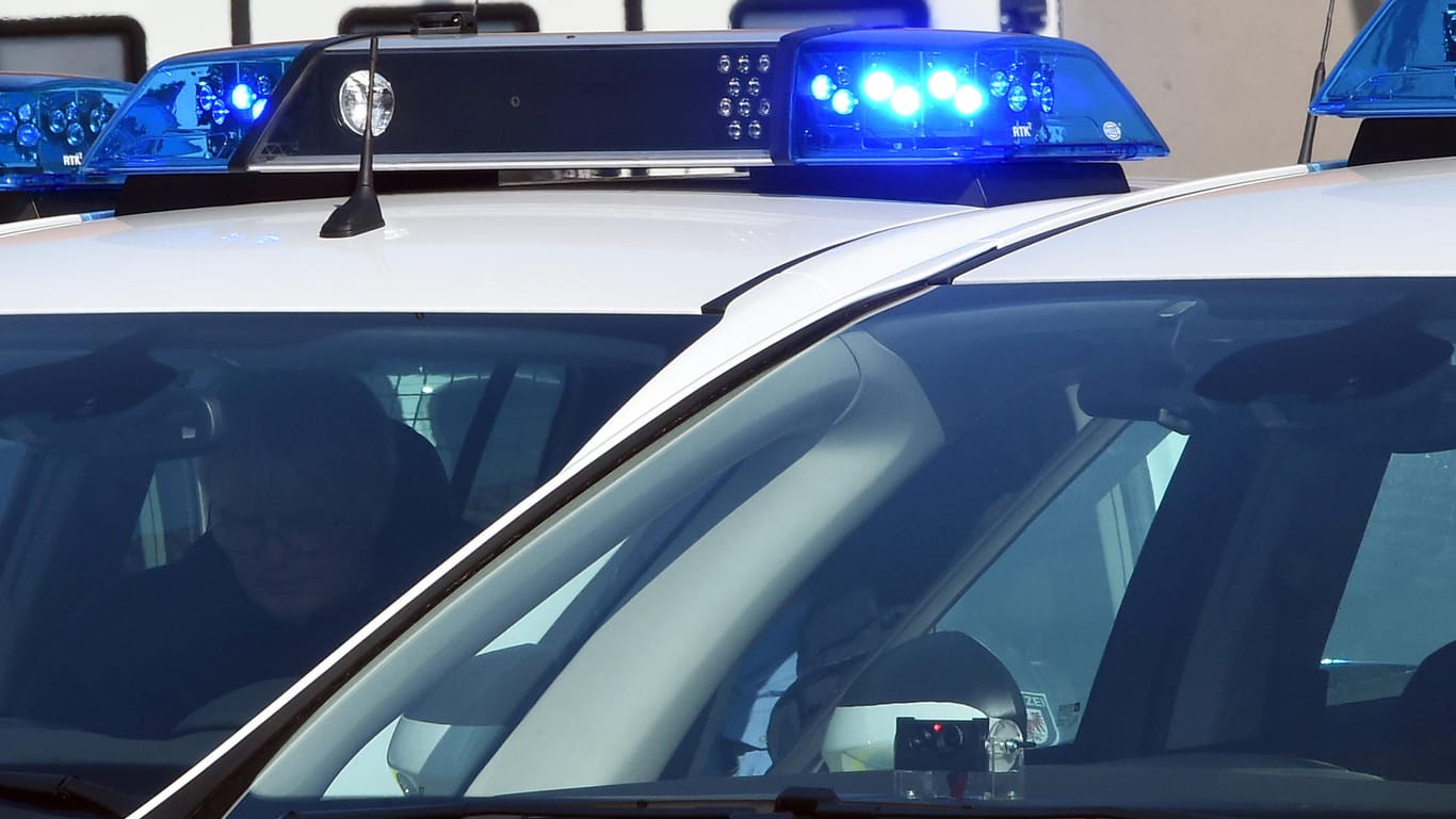 Ein Polizeifahrzeug steht mit eingeschaltetem Blaulicht: Die Berliner Polizei fahndet nach einem Mann, der einen anderen Mann im Park vergewaltigt haben soll.