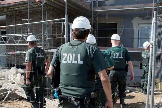 Zollbeamte durchsuchen bei einer Razzia gegen Schwarzarbeit eine Baustelle in Frankfurt am Main.