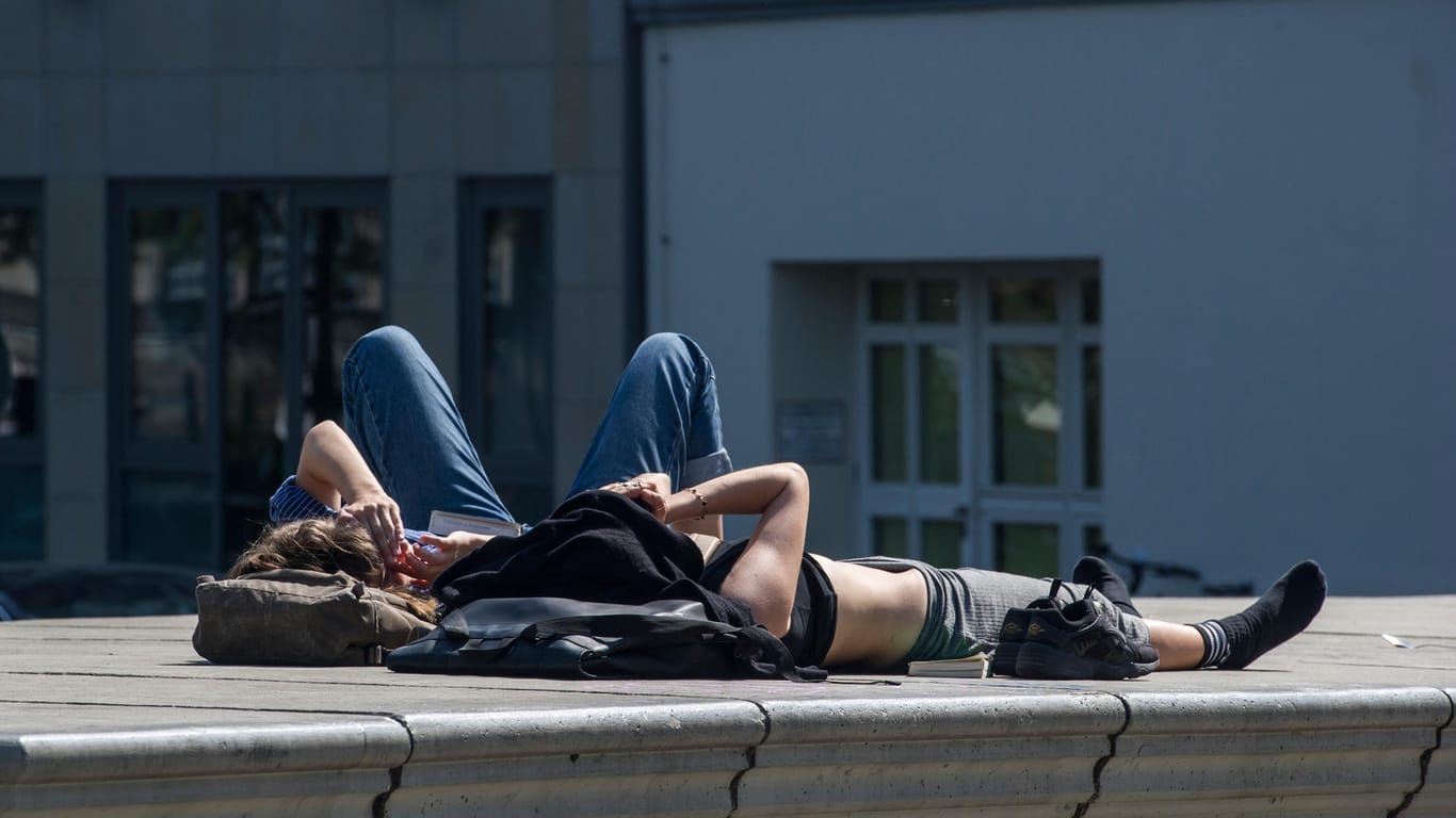 Sommervorboten in Berlin: Zwei Frauen liegen am Märkischen Ufer und genießen die Sonne.