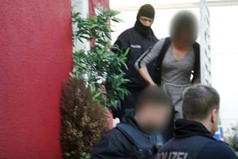 Polizisten führen in Bonn eine Person ab: Mehr als 100 Personen wurden bei der bundesweiten Aktion gegen eine Bande im Rotlichtmilieu vorläufig festgenommen.