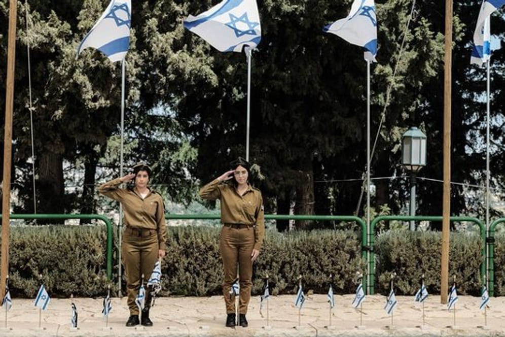 Israelische Soldatinnen salutieren in Jerusalem vor Soldatengräbern.