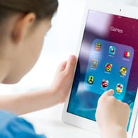Ein Kind mit Tablet in der Hand: Bei Apps für Kinder sollten Eltern unter anderem die Menge an Werbung und den Datenschutz kontrollieren.