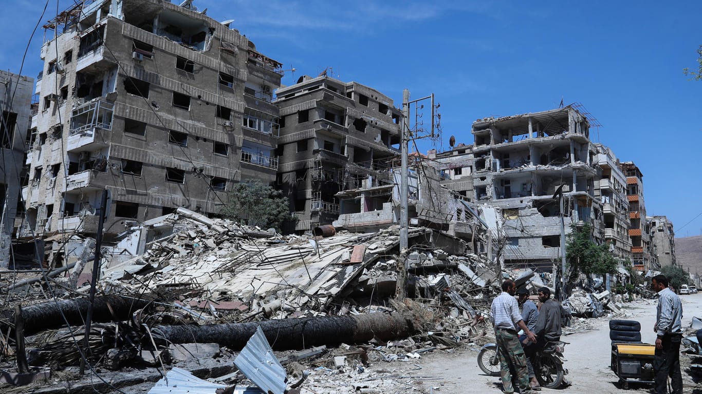 Menschen stehen vor zerstörten Gebäuden in der syrischen Stadt Duma: Die USA werfen Russland und Syrien Verzögerung der Untersuchung des mutmaßlichen Giftgasanschlags vor.