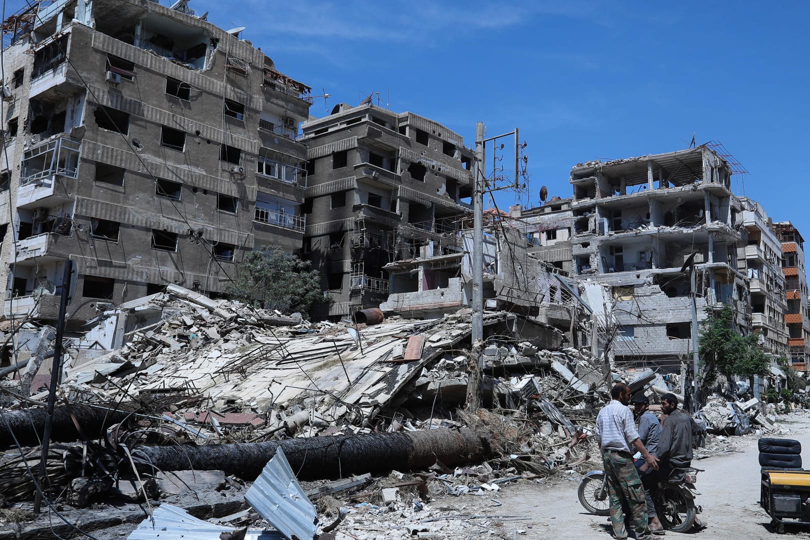 Menschen stehen vor zerstörten Gebäuden in der syrischen Stadt Duma: Die USA werfen Russland und Syrien Verzögerung der Untersuchung des mutmaßlichen Giftgasanschlags vor.