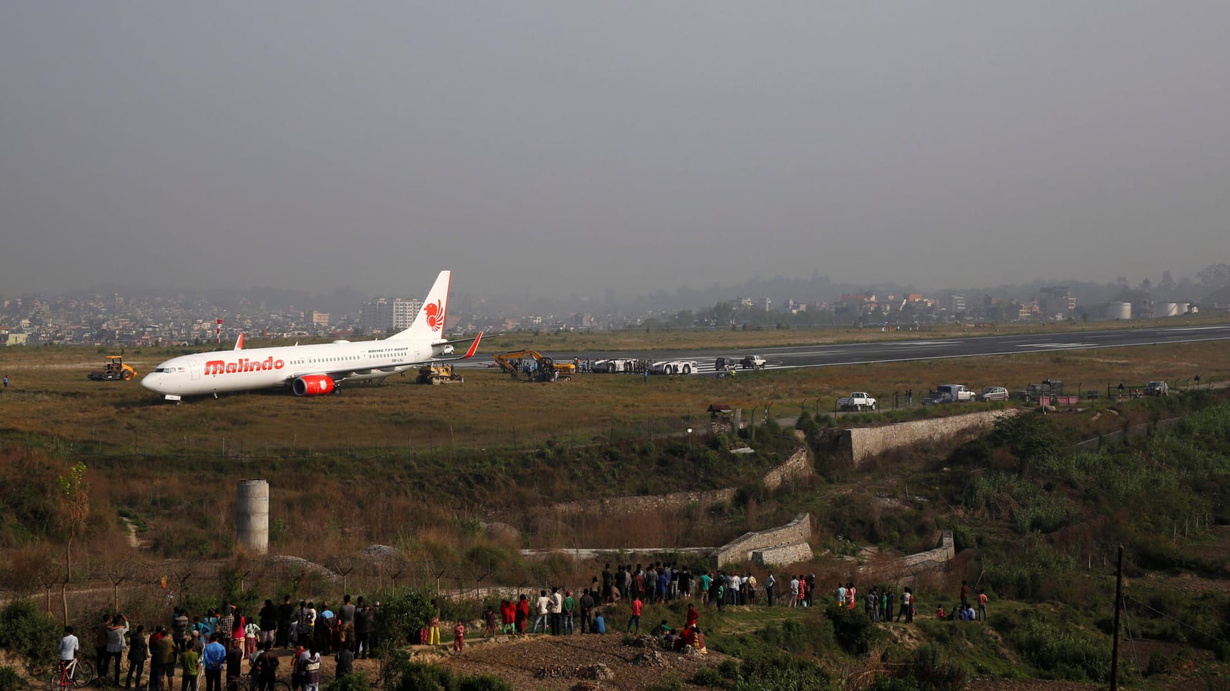 Die Boeing 737 auf der Rasenfläche am Ende der Startbahn: Viele Menschen haben sich versammelt, um den Vorfall zu begutachten.