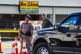 Zwei Polizisten in Trenton, Florida (USA) stehen vor einem "Ace China"-Restaurant und blicken in die Luft, während ein Hubschrauber über sie hinwegfliegt: In Trenton in Florida sind zwei Polizisten erschossen worden.
