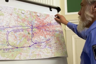 Ein Justizbeamter bringt eine Karte mit geplanten Flugrouten in Berlin an einer Wand an: Die Bürgerinitiative Kleinmachnnow wehrt sich gegen die festgelegten Routen. (Archivbild)