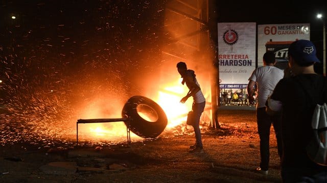 Ein Demonstrant wirft einen Reifen in ein Feuer, das von den Protestlern gelegt wurde. Ein Demonstrant wirft einen Reifen in ein Feuer, das von den Protestlern gelegt wurde.