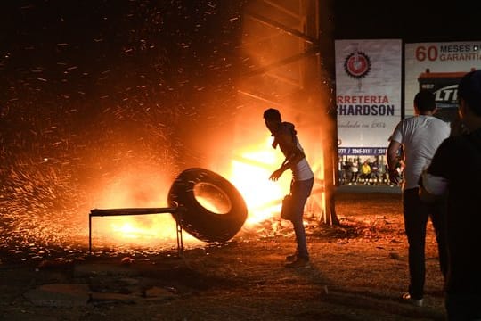 Ein Demonstrant wirft einen Reifen in ein Feuer, das von den Protestlern gelegt wurde.
