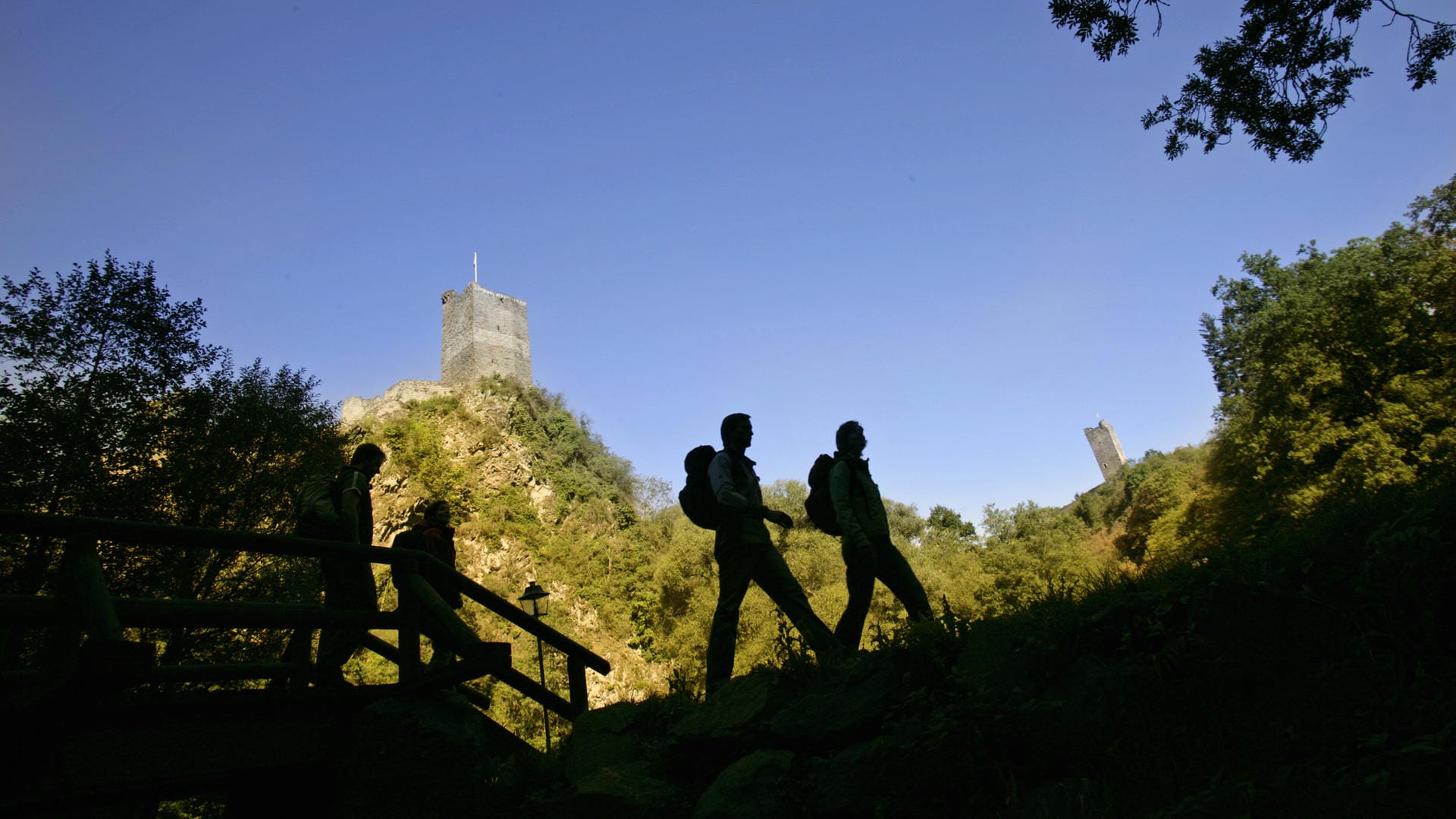 Wanderer vor den Kulissen der Burgruinen bei Manderscheid: Auf dem Lieserpfad bei Manderscheid (Rheinland-Pfalz) ist ein 80-jähriger Wanderer einen steilen Hang hinabgestürzt und verunglückt. (Archivbild)