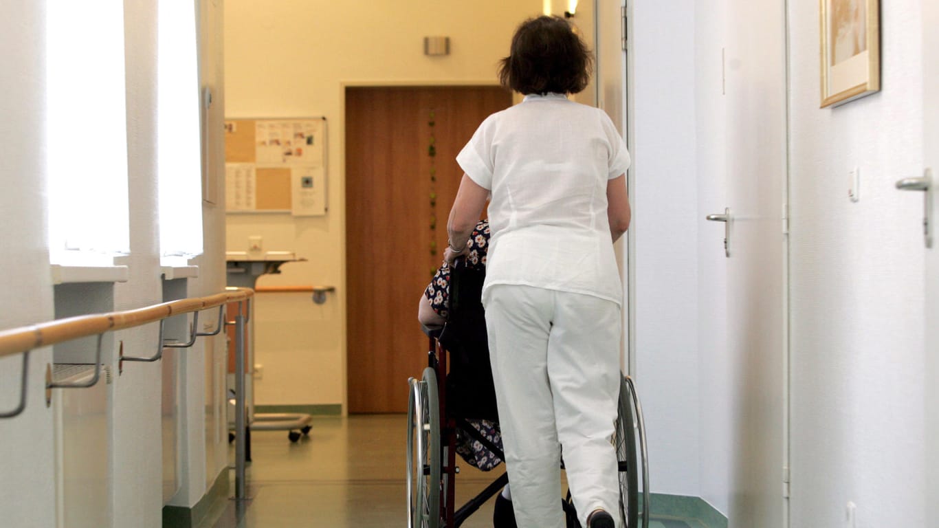 Pflegerin schiebt Pflegebedürftigen im Rollstuhl