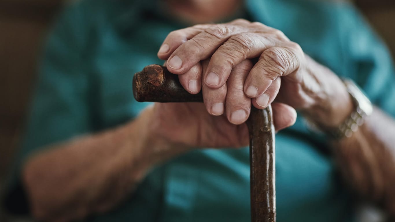 Mann stützt seine Hände auf einen Gehstock: Über die Sozialversicherungsbeiträge zahlen Arbeitnehmer in die gesetzliche Rente ein. Dabei finanzieren die derzeit Beschäftigten die aktuelle Rentengeneration.