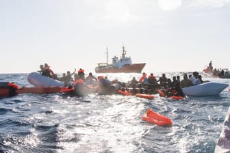 Zahlreiche Flüchtlinge werden während eines Rettungseinsatzes am vor der libyschen Küste geborgen: Im Hintergrund die "Aquarius" der Organisationen SOS Méditerranée und Ärzte ohne Grenzen.