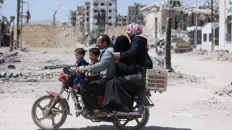 Eine Familie auf einem Motorrad in der syrischen Stadt Duma: Der Wiederaufbau Syriens könnte 200 Milliarden US-Dollar kosten.