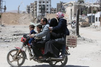 Eine Familie auf einem Motorrad in der syrischen Stadt Duma: Der Wiederaufbau Syriens könnte 200 Milliarden US-Dollar kosten.