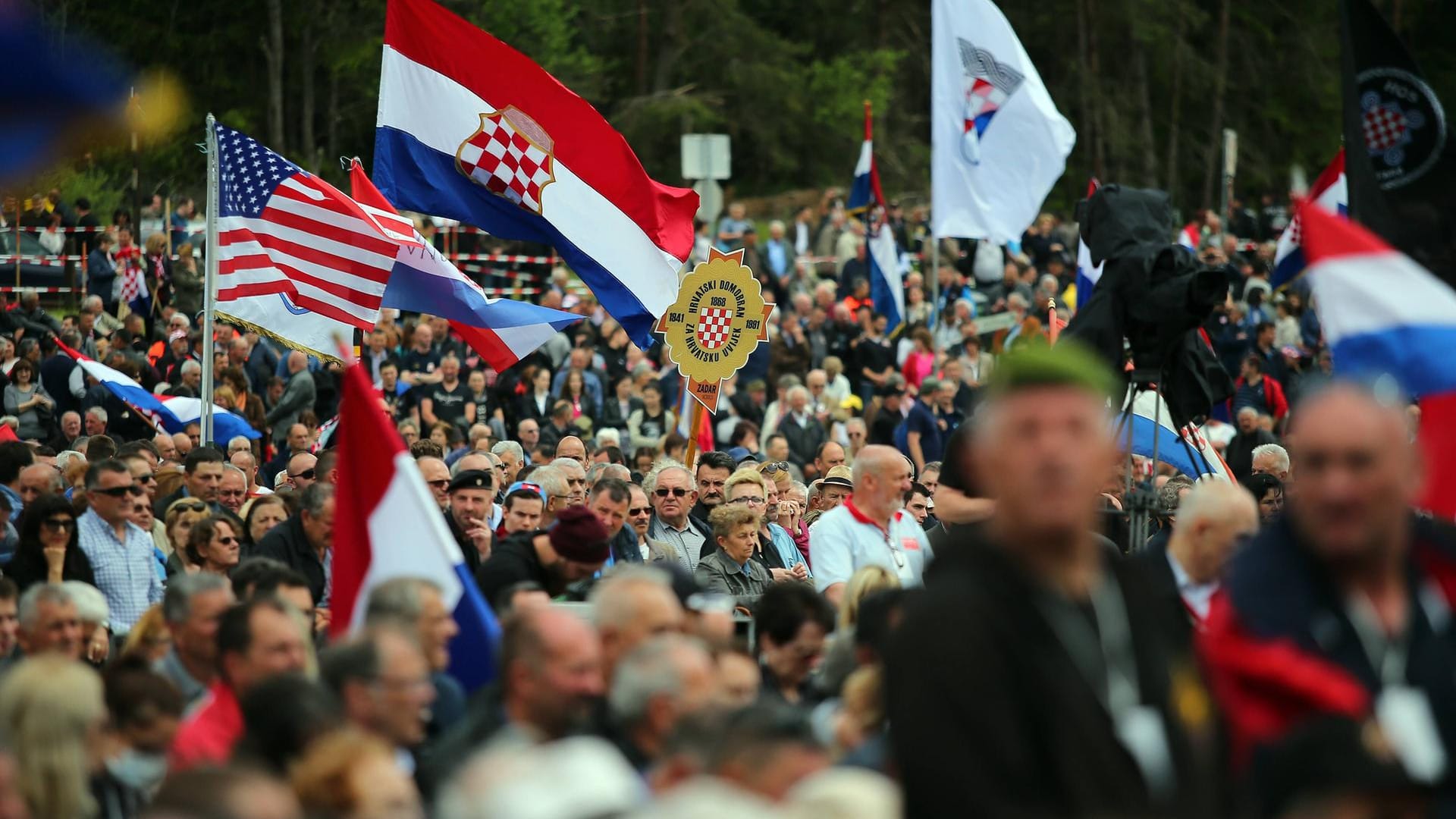 Menschenansammlung und Flaggen auf der vergangenen Gedenkfeier der Ustascha-Soldaten in Bleiburg: Zu der diesjährigen Gedenkfeier der Ustascha-Soldaten werden mit unter zahlreiche Neonazis erwartet. Die österreichische Regierung kann dieses Aufmarsch angeblich nicht verhindern. Menschenansammlung und Flaggen auf der vergangenen Gedenkfeier der Ustascha-Soldaten in Bleiburg: Zu der diesjährigen Gedenkfeier der Ustascha-Soldaten werden mit unter zahlreiche Neonazis erwartet. Die österreichische Regierung kann dieses Aufmarsch angeblich nicht verhindern.