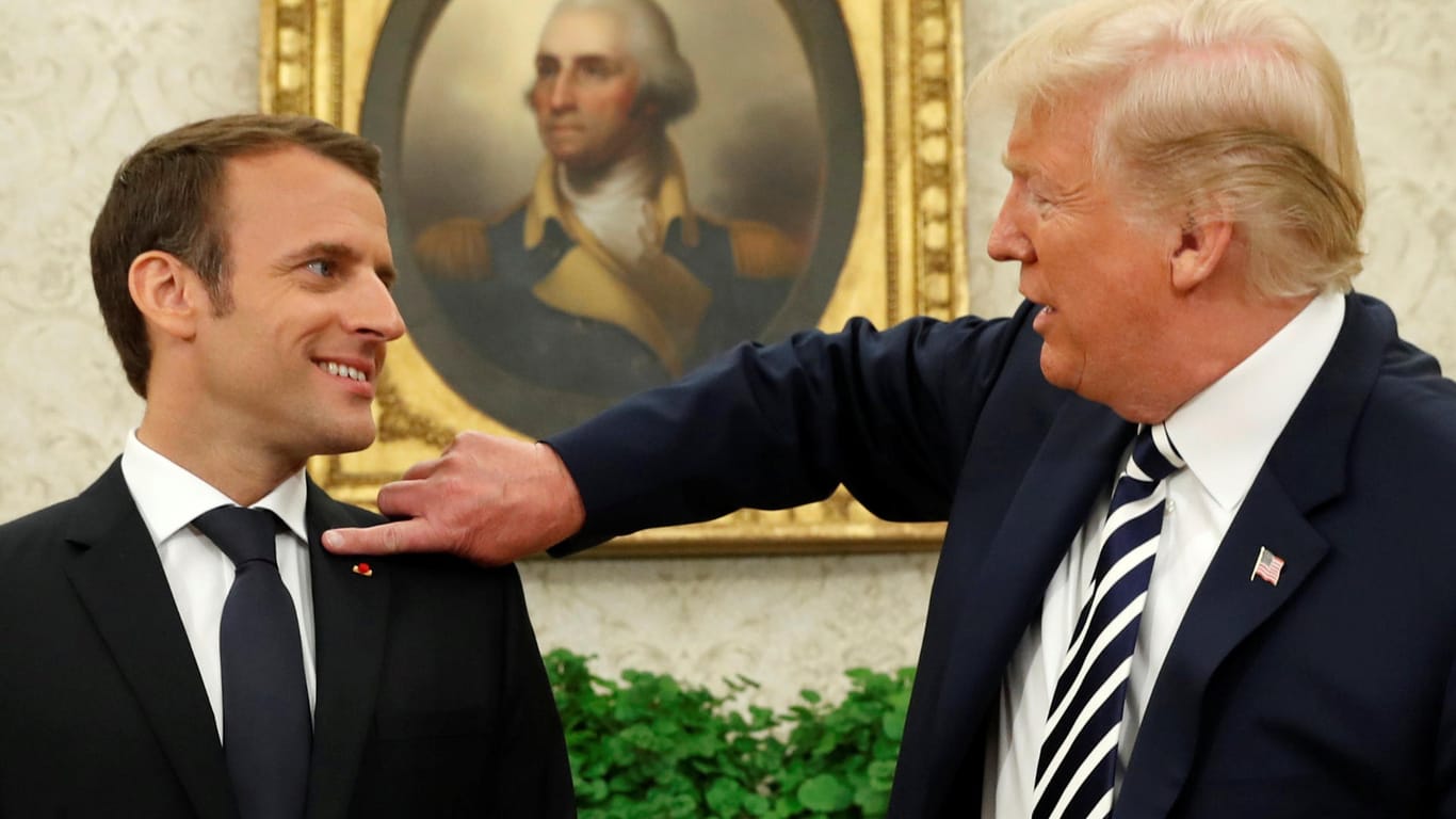 US-Präsident Donald Trump wedelt dem französischen Präsidenten Emmanuel Macron eine Schuppe vom Revers.