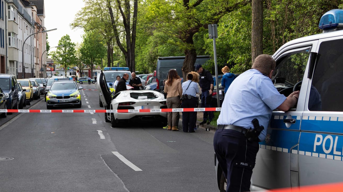 Die Polizei sichert den Tatort der Schießerei in Köln, bei der zwei Männer schwer verletzt wurden: Einer der Männer soll der Chef der Rockergruppe "Bandidos" sein. Ihm soll auch der weiße Lamborghini gehören.